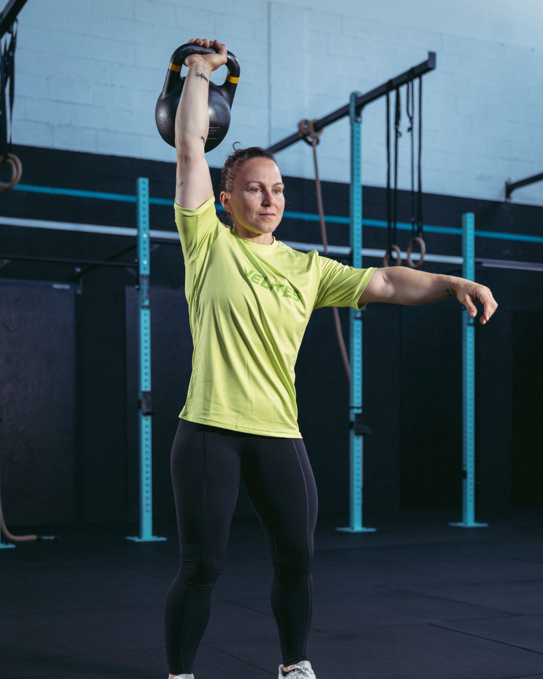 Female athlete training with a kettlebell wearing a Velites Holo t-shirt in a box