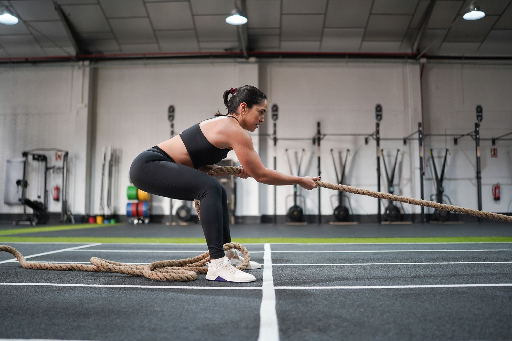 Woman crossfit training in Velites Minimal 1.0 Ivory White barefoot shoes doing battle rope pulls in the gym box