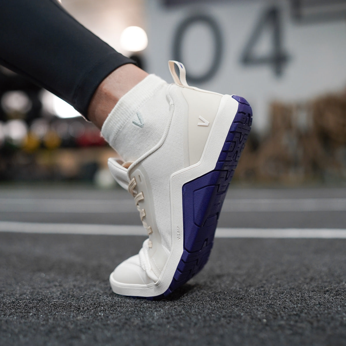 Woman crossfit training in Velites Minimal 1.0 Ivory White barefoot shoes doing deep lunges with extreme flexibility in the gym box
